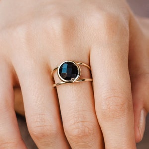 Black onyx double band ring in 14K solid gold on the middle finger of a female model.