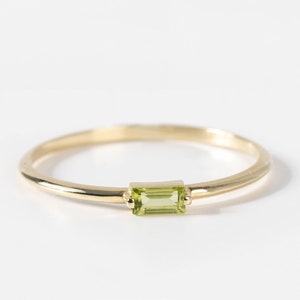 Natural green peridot ring in 14K yellow gold for women. The stone is baguette cut.
