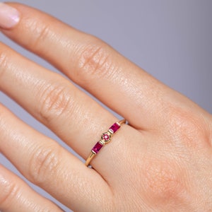 14K solid gold stacking ring with natural rubies in minimalist design on the middle finger of the model.