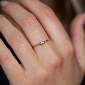 Minimalist solid gold ring with a genuine blue sapphire stone in baguette cut.