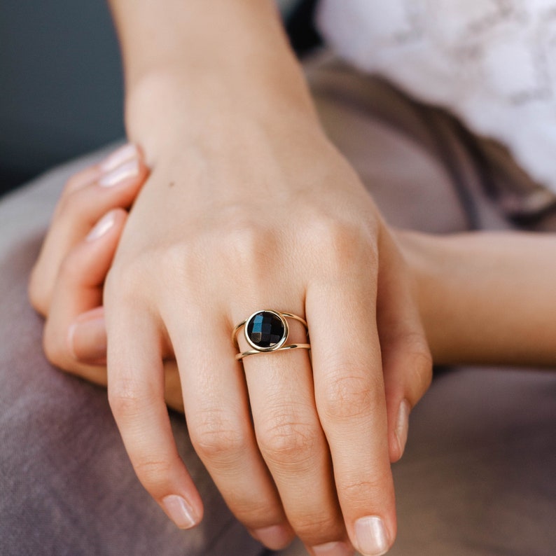 Black onyx double band ring in 14K solid gold on the middle finger of a female model.