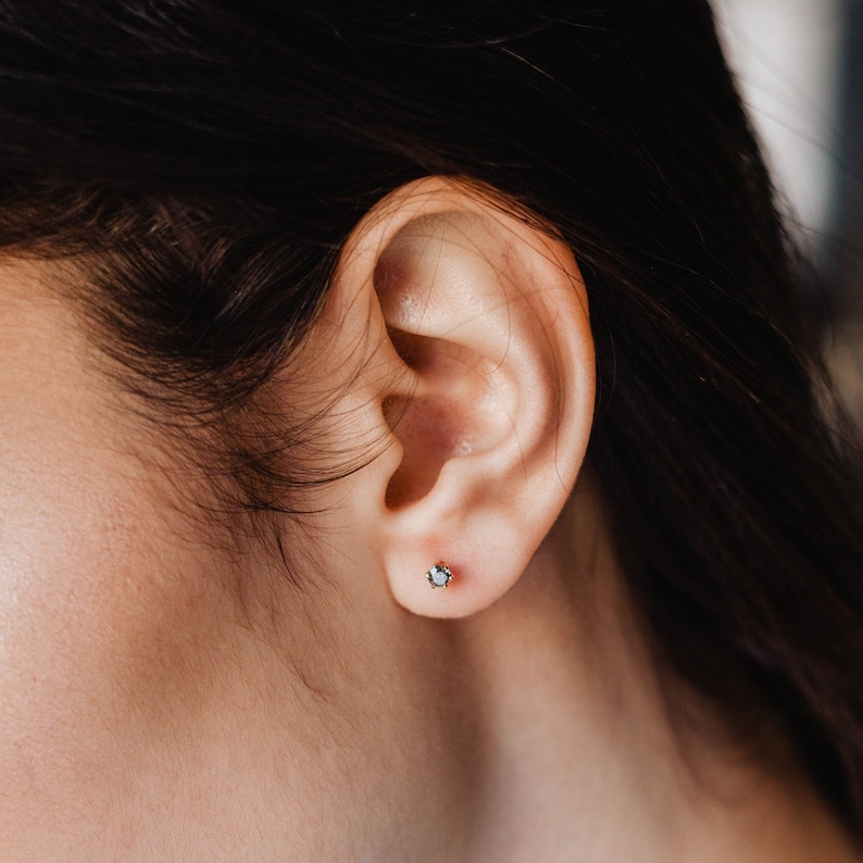 Solid gold gray diamond stud earrings on the model's ear