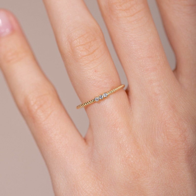 Dainty 3 diamond ring with a twisted band on finger