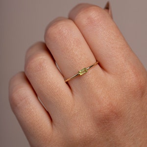 Solid gold peridot ring on a model's finger, dainty and minimalist.