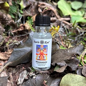 May include: A small, clear glass bottle with a black cap. The bottle is labeled "Sun's Eye" and "Moonstone Concentrated Aroma 1/2 fl oz (15 ml)".