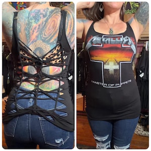May include: Black tank top with the Metallica logo and "Master of Puppets" text. The back of the top is cut out with a crisscross design. The top is paired with blue jeans.