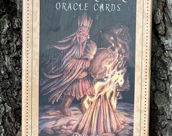 May include: A box of Ancestor Spirit Oracle Cards illustrated by Jade Sky. The box features a colorful illustration of a person in traditional clothing holding a drum in front of a fire.