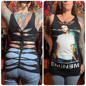May include: Black tank top with cut-out design on the back and a graphic of Eminem on the front. The tank top is paired with blue jeans. The back of the tank top has a unique woven design.