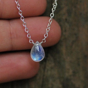 May include: A silver chain necklace with a teardrop-shaped moonstone pendant.