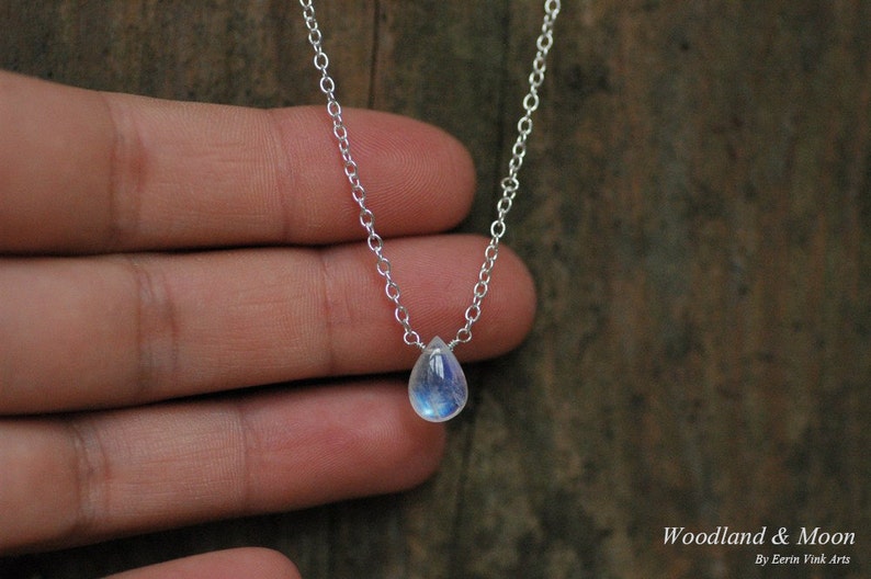 May include: A silver chain necklace with a teardrop-shaped moonstone pendant.