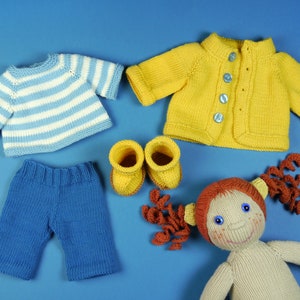 Könnte beinhalten: Ein Strick-Puppen-Outfit-Set mit einem blau-weiß gestreiften Pullover, einer blauen Hose und einer gelben Strickjacke. Das Set enthält auch ein Paar gelbe Strick-Stiefeletten und eine Strickpuppe mit braunen Haaren.