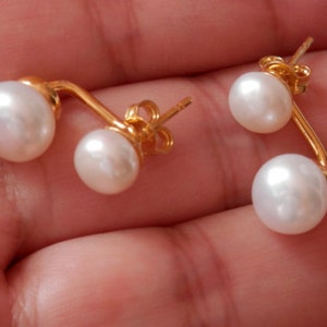 May include: A pair of gold-tone earrings with two white pearls on each earring.
