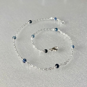 Peut inclure: Un bracelet de cheville en cha&icirc;ne argent avec des perles de pierres pr&eacute;cieuses bleues et noires.