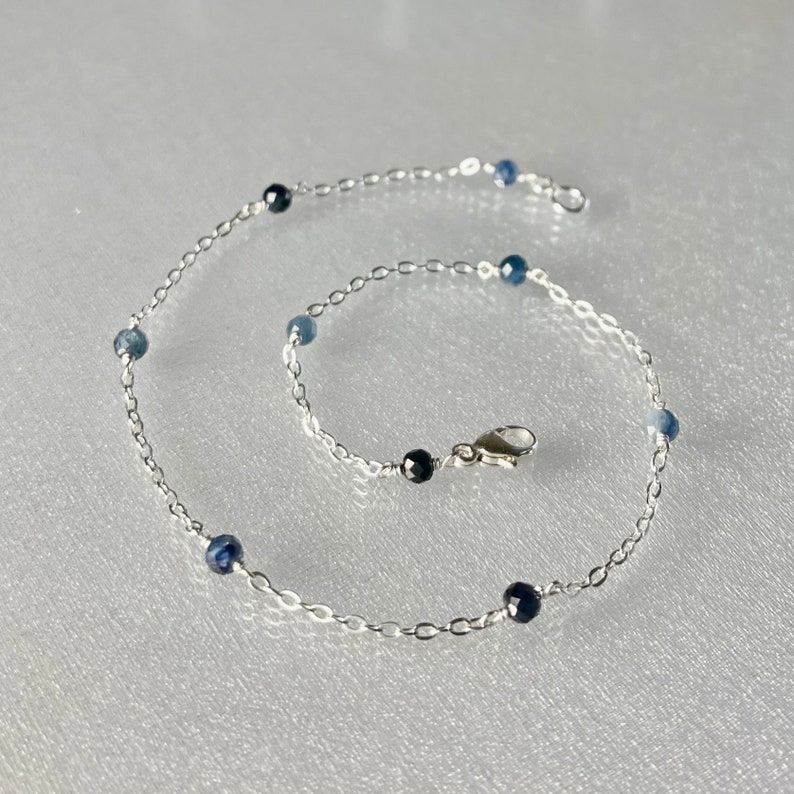 Peut inclure: Un bracelet de cheville en cha&icirc;ne argent avec des perles de pierres pr&eacute;cieuses bleues et noires.
