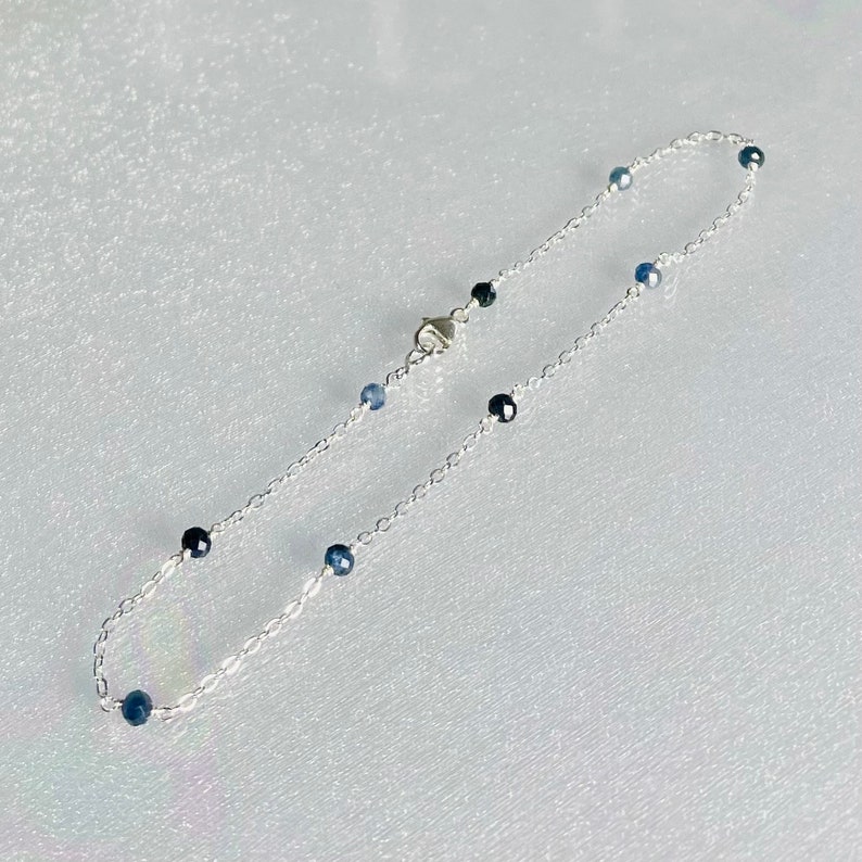 Peut inclure: Un bracelet de cheville en argent avec de petites perles de pierres pr&eacute;cieuses bleues.