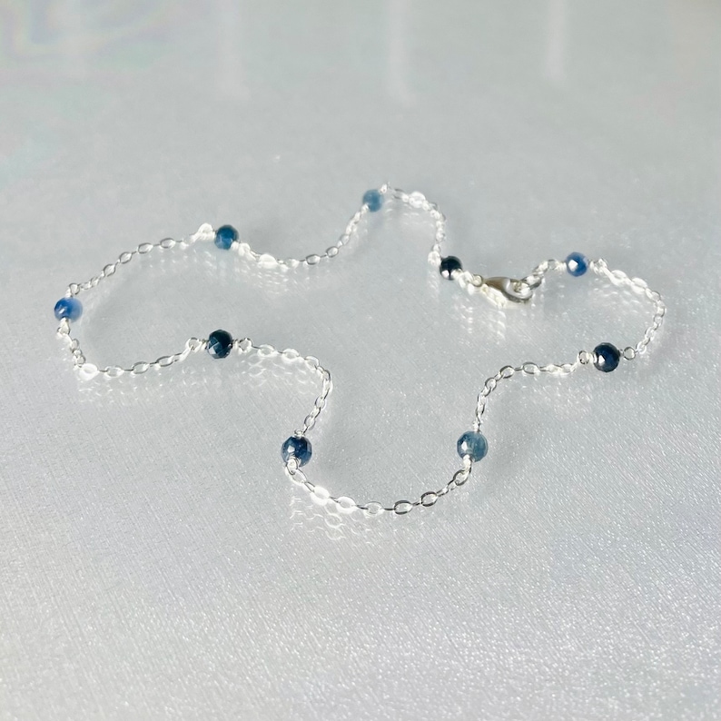 Peut inclure: Un collier en cha&icirc;ne argent avec de petites perles de pierres pr&eacute;cieuses bleues.
