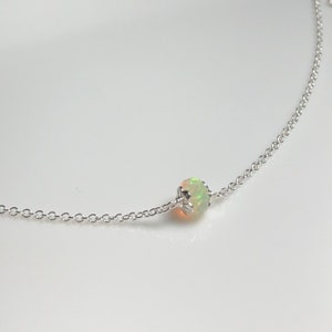 May include: A delicate silver chain necklace with a single white opal gemstone pendant.
