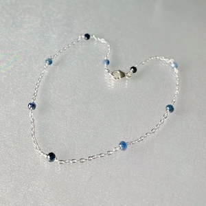 Peut inclure: Un bracelet de cheville fin en argent avec de petites perles de pierres pr&eacute;cieuses bleues.