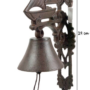 May include: A cast iron door bell with a sailboat design and a bell with a brown rope. The bell is 29 inches tall.