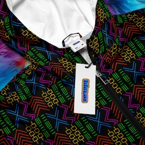 Könnte beinhalten: Eine schwarze Kapuzenjacke mit einem bunten geometrischen Muster. Die Jacke hat einen Reißverschluss und ein weißes Etikett mit dem Text "Ultra.com" darauf.