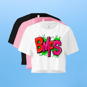 May include: Three crop tops in black, pink, and white. The white crop top features the letters "BMFS" in red and pink, outlined in black, with green splatter accents. The shirts are displayed on a light blue background.