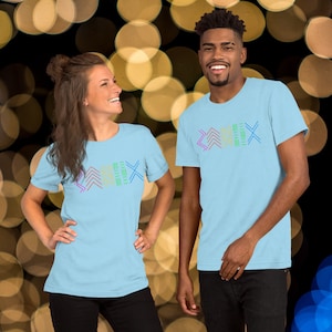May include: Two people wearing light blue t-shirts with the word "ZEMIX" in colorful, geometric designs. The shirts have short sleeves and a crew neck. The background is blurred with golden bokeh lights.