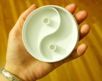 Może przedstawiać: Biała plastikowa foremka do ciasteczek w kształcie symbolu yin yang. Foremka ma dwa okrągłe wycięcia w środku.