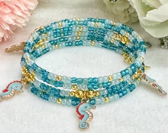 May include: A multi-strand beaded bracelet with blue and gold beads. The bracelet has three seahorse charms attached.