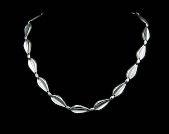 May include: A silver necklace with a chain made of small, teardrop-shaped links.