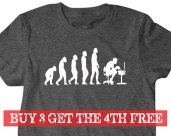 May include: A dark gray t-shirt with a white graphic of the evolution of man, ending with a man sitting at a computer. The text "BUY 3 GET THE 4TH FREE" is printed in red at the bottom of the shirt.