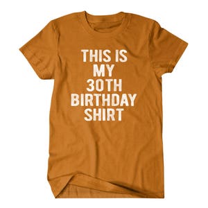Puede incluir: Una camiseta amarilla mostaza con el texto "This is my 30th Birthday Shirt" en blanco.