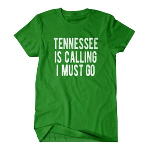 May include: Green t-shirt with white text that reads "Tennessee is calling I must go."