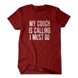 May include: Red t-shirt with the text "My couch is calling I must go" in white.