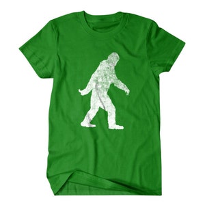Puede incluir: Camiseta verde con una silueta blanca de Bigfoot caminando.