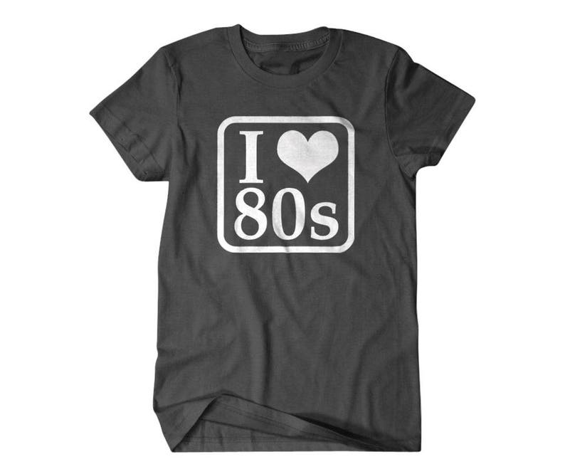 May include: A dark gray t-shirt with a white square graphic that says "I love 80s" with a heart in place of the "o".