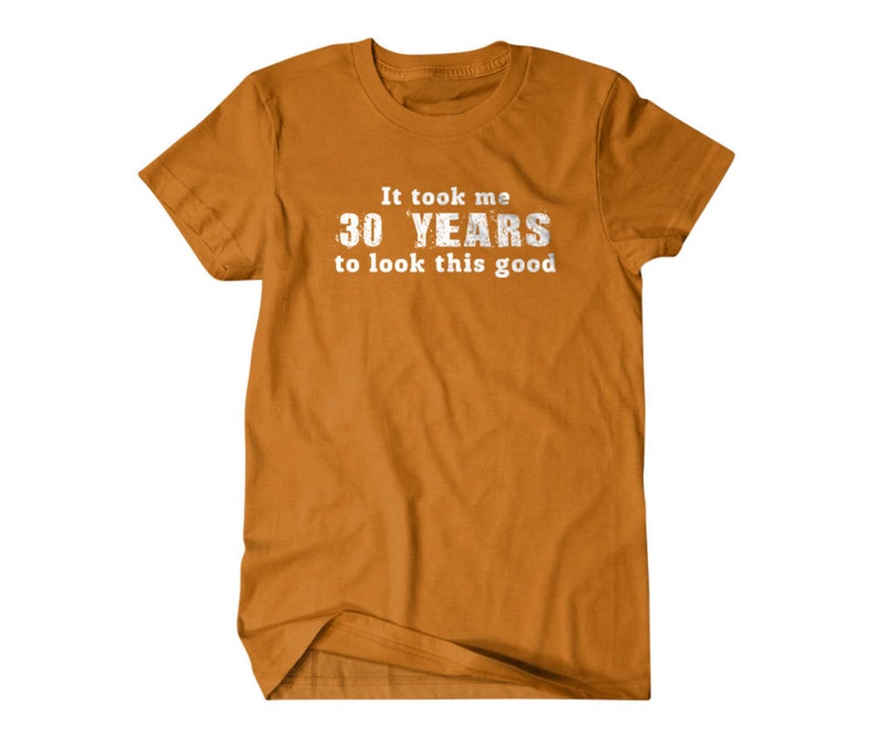 May include: A mustard yellow t-shirt with the text "It took me 30 YEARS to look this good" printed in white.