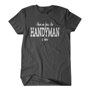 Op de afbeelding: Donkergrijs T-shirt met witte tekst die "Have no fear... the HANDYMAN is here" luidt.
