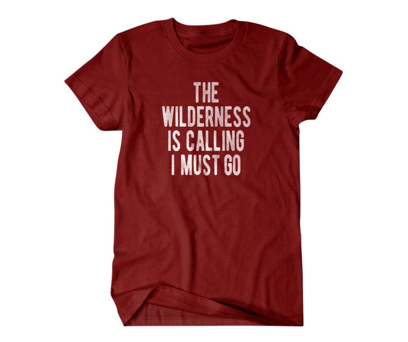May include: Red t-shirt with white text that reads "The Wilderness is Calling I Must Go."