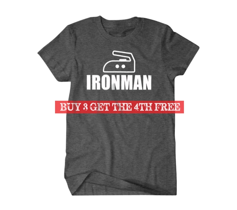 Puede incluir: Una camiseta gris oscuro con un icono de plancha blanco y el texto "IRONMAN" impreso en la parte delantera. El texto "BUY 3 GET THE 4TH FREE" est&aacute; impreso en rojo debajo del dise&ntilde;o.