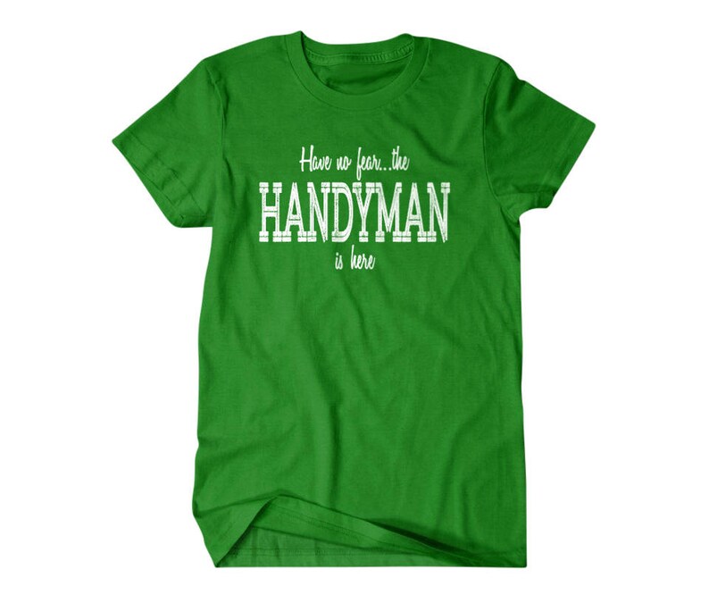 Op de afbeelding: Groen T-shirt met witte tekst die "Have no fear... the HANDYMAN is here." luidt.