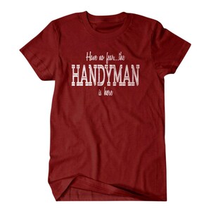 Op de afbeelding: Rood T-shirt met witte tekst die "Have no fear... the HANDYMAN is here." luidt.