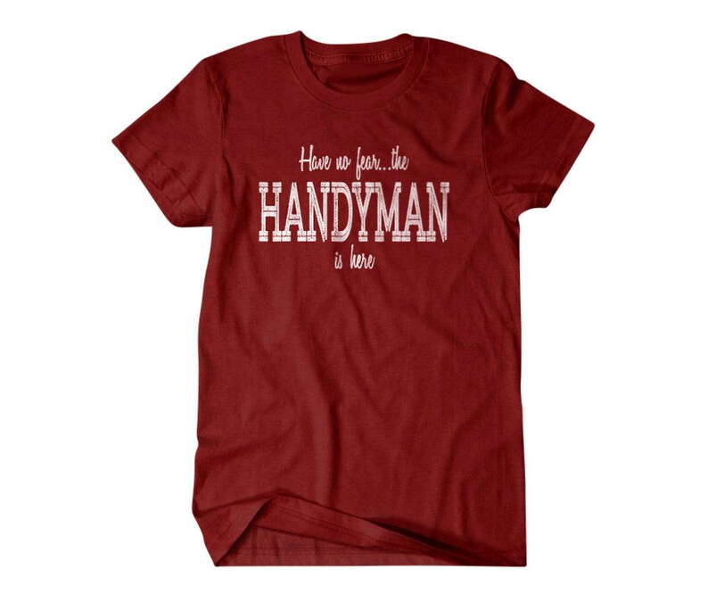 Op de afbeelding: Rood T-shirt met witte tekst die "Have no fear... the HANDYMAN is here." luidt.