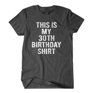 Puede incluir: Una camiseta gris oscuro con el texto "This is my 30th Birthday Shirt" impreso en blanco.