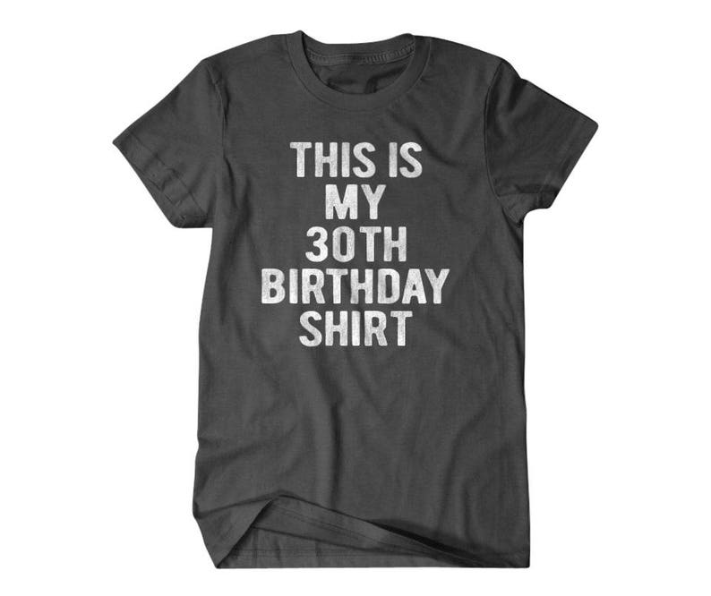 Puede incluir: Una camiseta gris oscuro con el texto "This is my 30th Birthday Shirt" impreso en blanco.