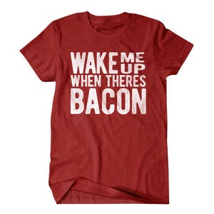 May include: Red t-shirt with white text that reads "Wake Me Up When There's Bacon".