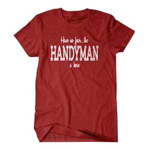 Op de afbeelding: Rood T-shirt met witte tekst die "Have no fear... the HANDYMAN is here" zegt.