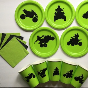 May include: Green and black paper plates and cups with a silhouette of an ATV on each. The plates and cups are perfect for a party or event.