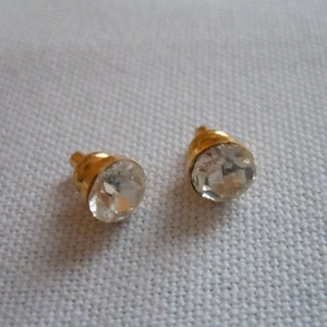 May include: A pair of gold stud earrings with clear round rhinestones.