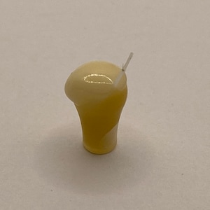 May include: A miniature ceramic glass with a yellow and white swirl design, filled with a white liquid and topped with a white straw.