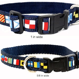 May include: Navy blue dog collar with nautical flag pattern. The collar has a black plastic buckle and a metal D-ring. The collar is 1 inch wide and 5/8 inch wide.